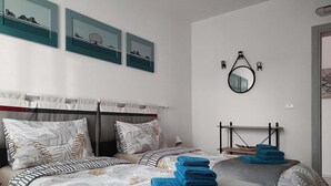 Una habitación de hotel con dos camas, un cabecero, un espejo montado en la pared y obras de arte.