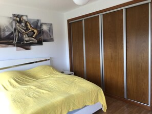 Un dormitorio con una cama, un armario de madera y una obra de arte colgada en la pared.