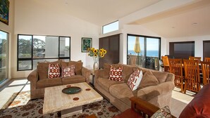 A spacious living room with two sofas, a coffee table, and a dining area with wooden chairs and a table. - Paradise Awaits - Panoramic Ocean Views, big space (Solana Beach)
