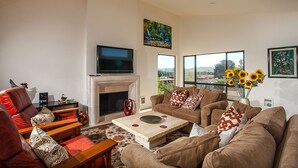 A living room with a fireplace, sofas, a coffee table, and a TV. - Paradise Awaits - Panoramic Ocean Views, big space (Solana Beach)
