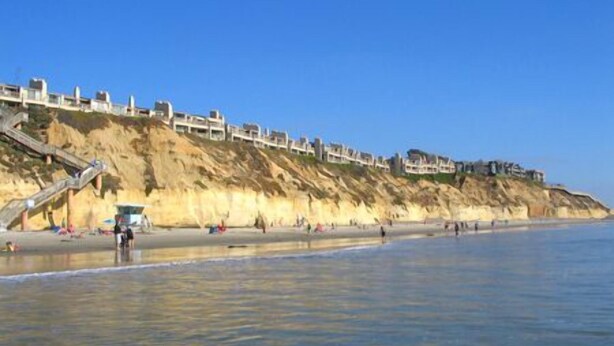 A coastal hotel with a staircase leading to the beach, a sandy beach, and a clear blue sky. - Paradise Awaits - Panoramic Ocean Views, big space (Solana Beach)