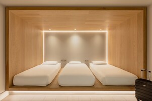 Una habitación con tres camas individuales, paneles de madera e iluminación empotrada.