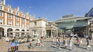 A bustling outdoor market area with historic buildings and a covered walkway.