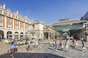 Un mercado al aire libre animado con edificios históricos y un pasillo cubierto.