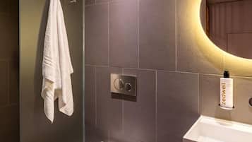 A modern bathroom with a toilet, a sink, and a glass shower enclosure.