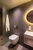 Ein modernes Badezimmer mit Toilette, Waschbecken und einer Duschkabine aus Glas.