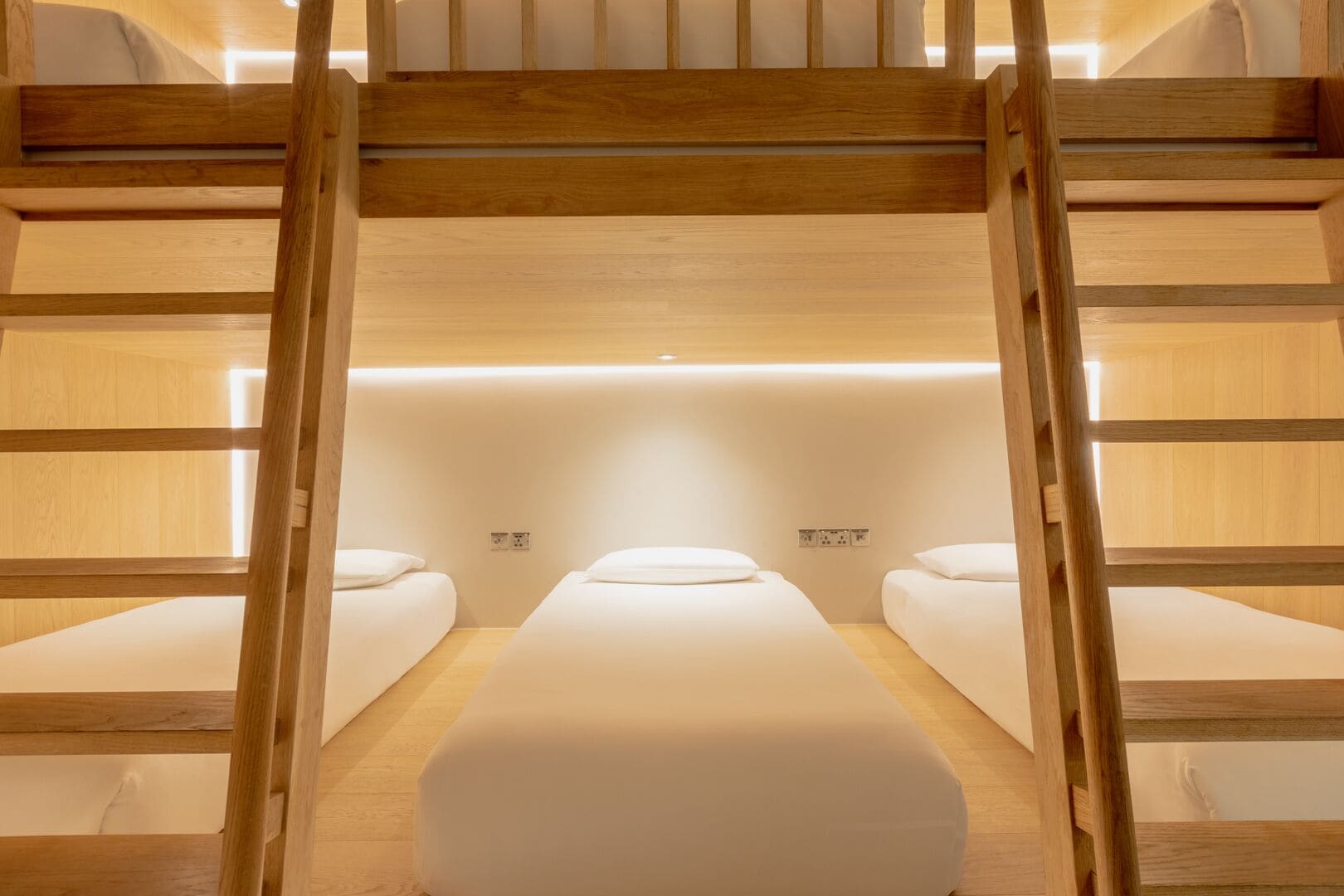 A bunk bed room with two beds and a central bed, wooden walls, and a simple, clean design.