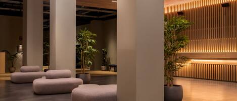 A modern lobby with large columns, seating areas, and potted plants.