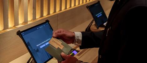 A person using a tablet at a reception desk with a wooden panel wall in the background.