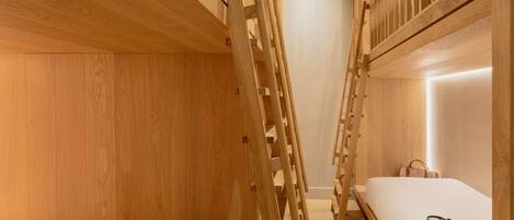 Habitación con literas, paredes de madera y una escalera.