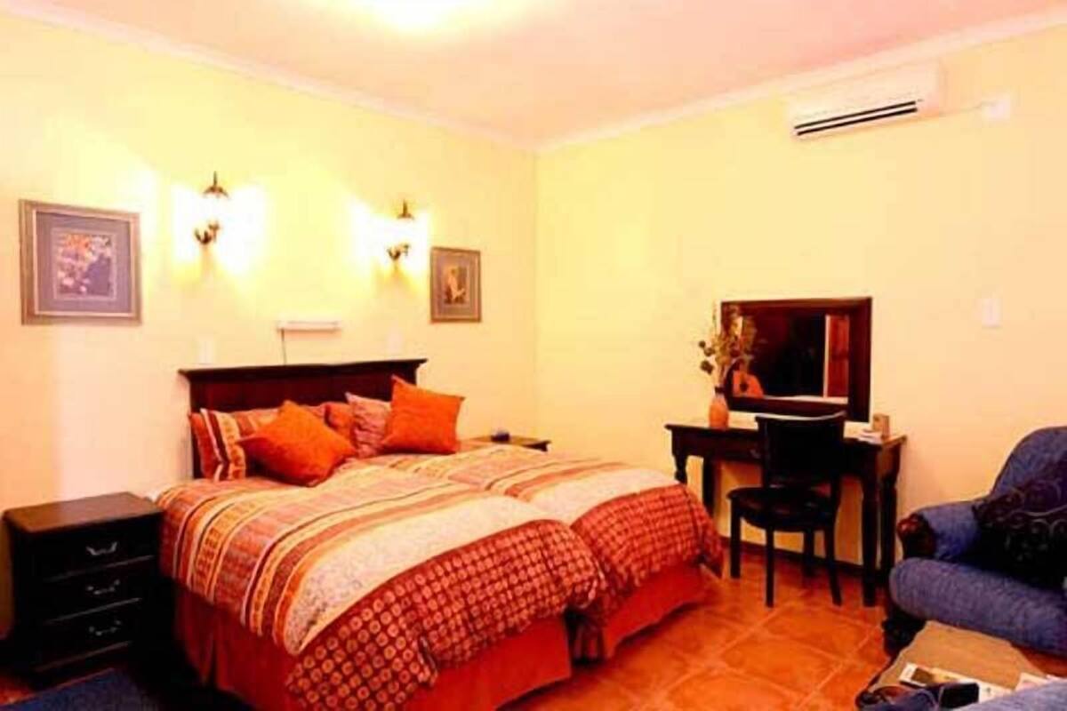 A bedroom with a double bed, a desk, a chair, and a television.