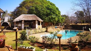 Uma cabana com telhado de palha, piscina e jardim.