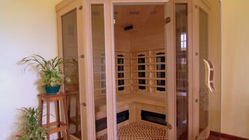 A sauna with a wooden interior, a wooden bench, and a glass door.