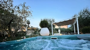 Ein Whirlpool mit Steinwand und einer Pergola in einem Garten.
