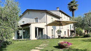 Ein zweistöckiges Haus mit Terrasse und Garten.