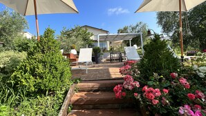 Eine Terrasse mit Gartenmöbeln, einer Pergola und einem Rosengarten.