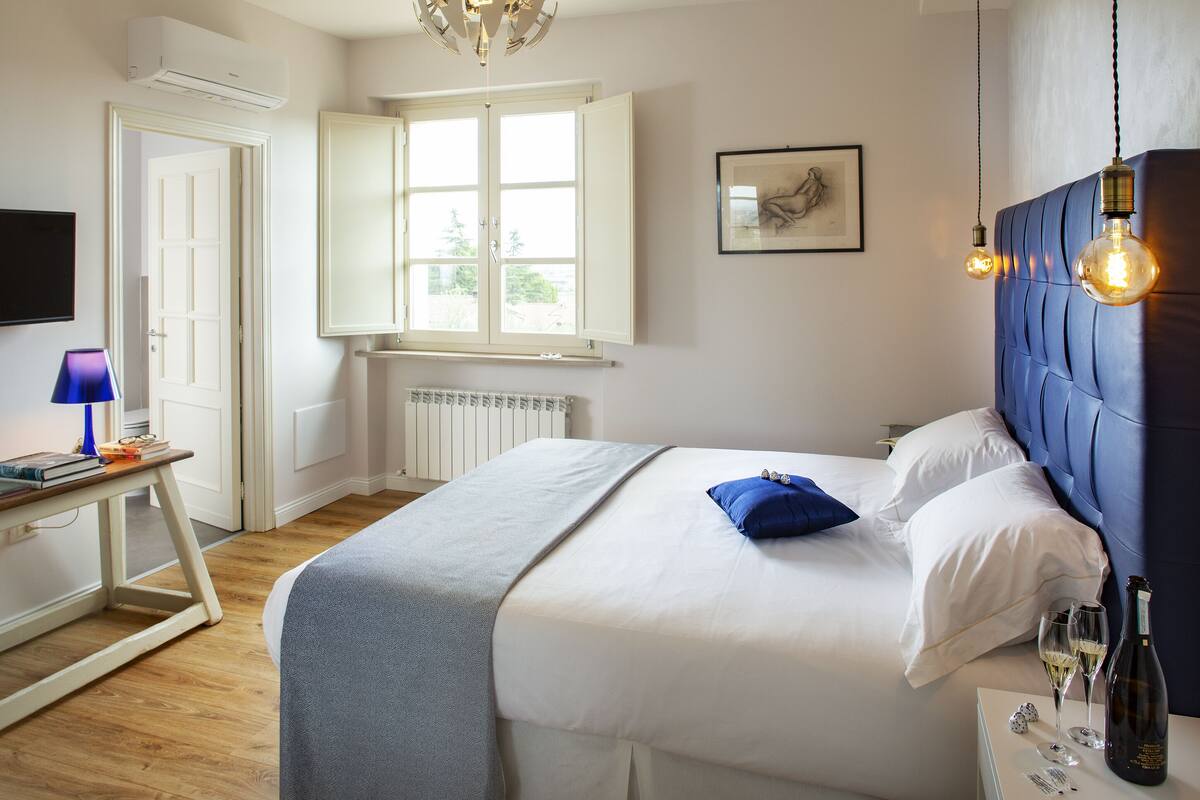 A bedroom with a bed, bedside table, and a window.