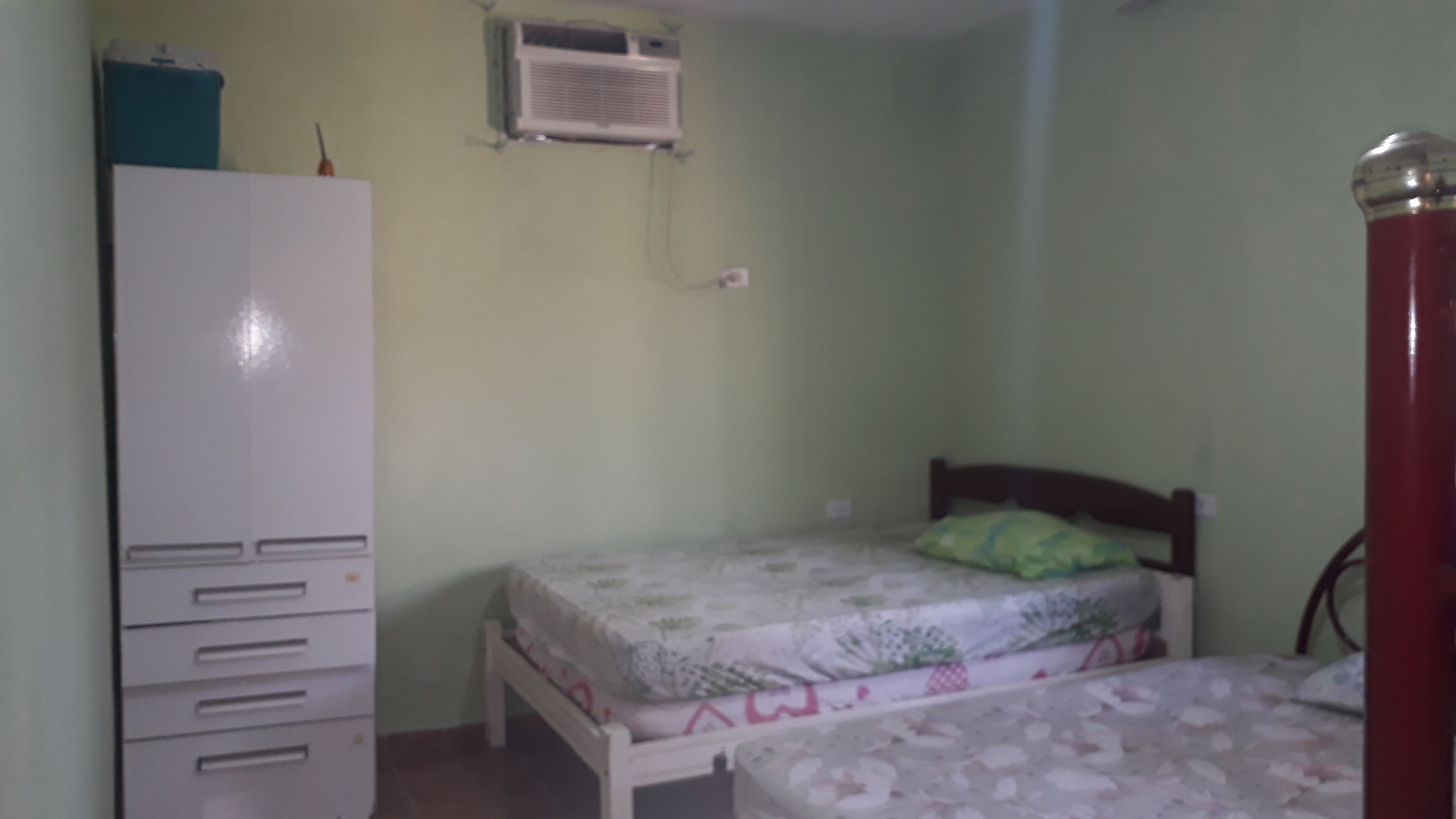 Een slaapkamer met een bed, een kledingkast en een airconditioning aan de muur.