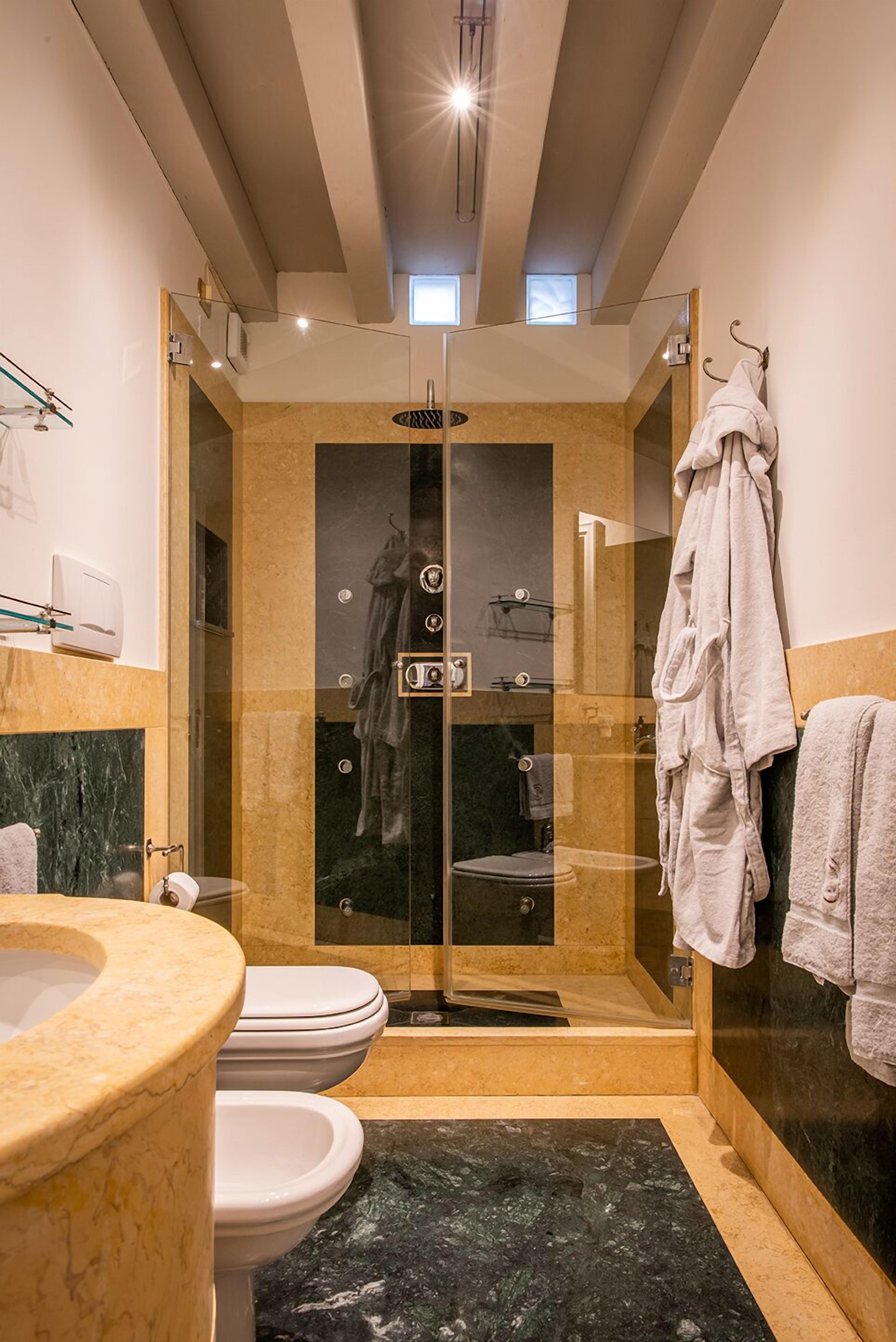 A modern bathroom with a glass-enclosed shower, a marble sink, and a toilet.