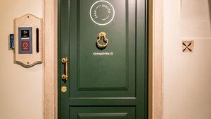 A green door with a brass knocker and a circular logo. - Casa Giotto (Padova)