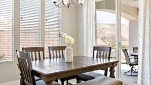 A dining area with a wooden table, chairs, a vase with flowers, and a view through large glass doors. - Curtis Ladera RV PAD, Basketball Hoop, Community Pool (Washington)