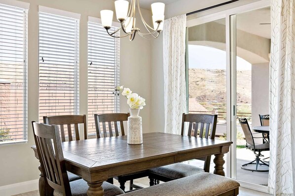 A dining area with a wooden table, chairs, a vase with flowers, and a view through large glass doors. - Curtis Ladera RV PAD, Basketball Hoop, Community Pool (Washington)