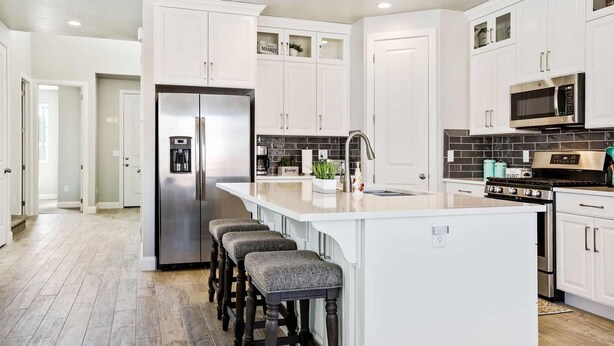 A modern kitchen with white cabinetry, stainless steel appliances, and a large island with bar stools. - Curtis Ladera RV PAD, Basketball Hoop, Community Pool (Washington)
