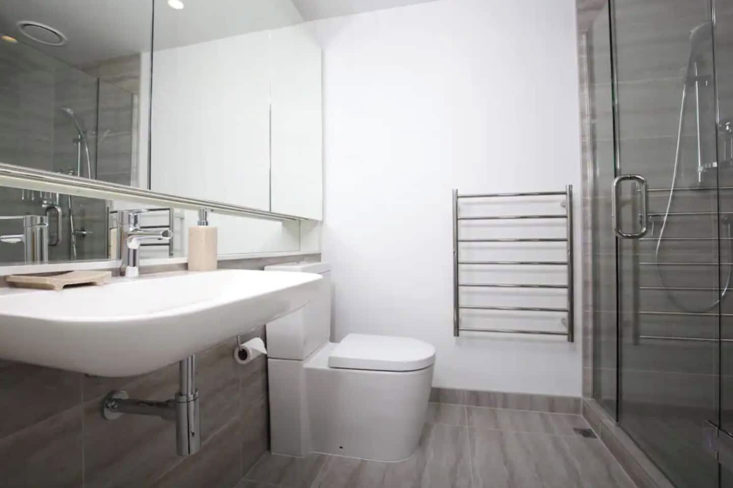 A modern bathroom with a large sink, toilet, and glass shower enclosure.