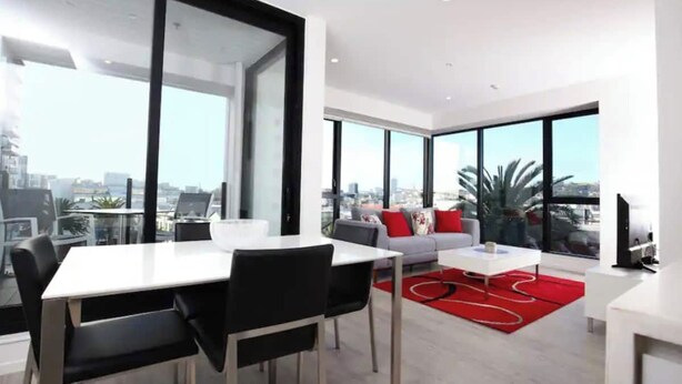 A modern living room with a dining area, large windows, and a city view.