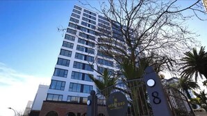A modern high-rise building with a prominent entrance gate and a sign indicating 'Herford Residences'.