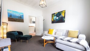 En moderne stue med sofa, lænestol, sofabord og billeder på væggene.