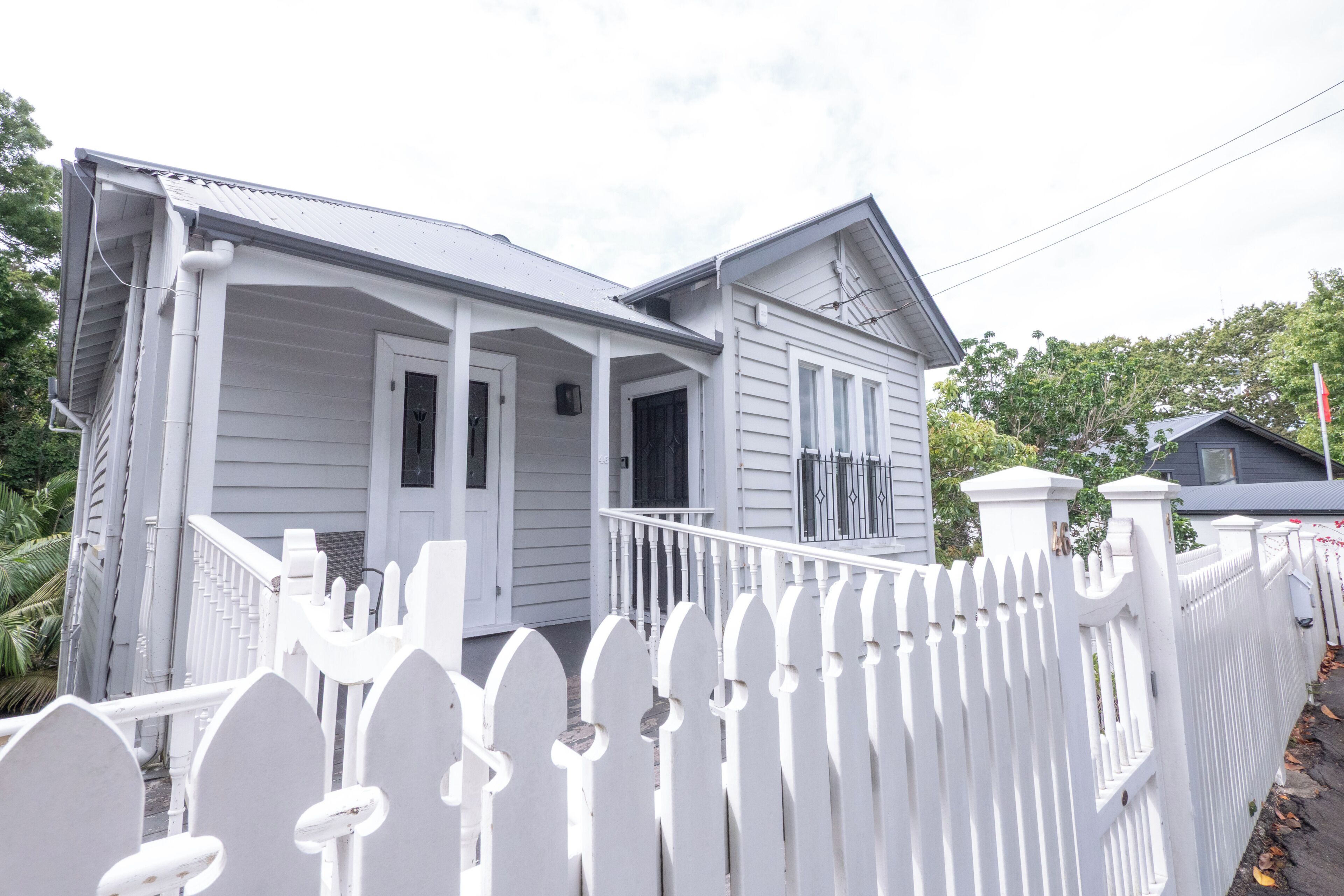 A two-story house with a porch and a white picket fence.