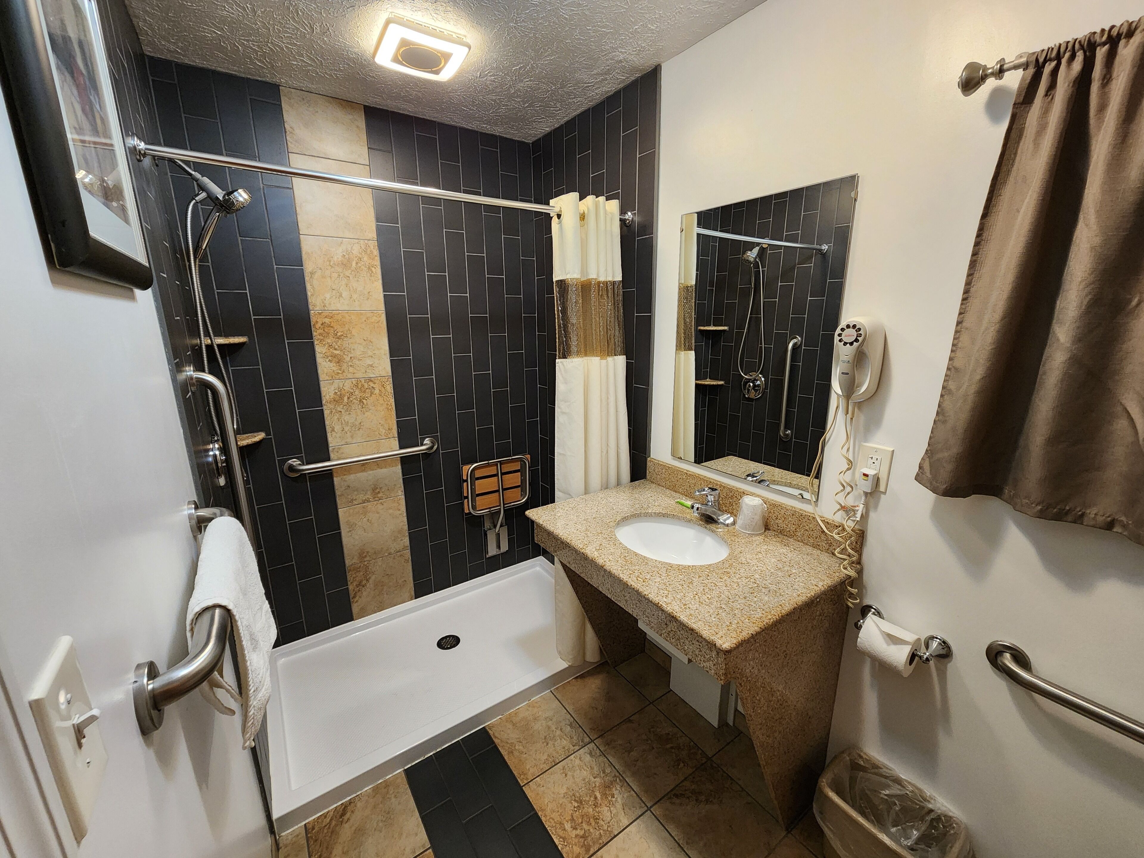 Une salle de bain équipée d’une douche, d’un lavabo, d’un miroir et d’un porte-serviettes.