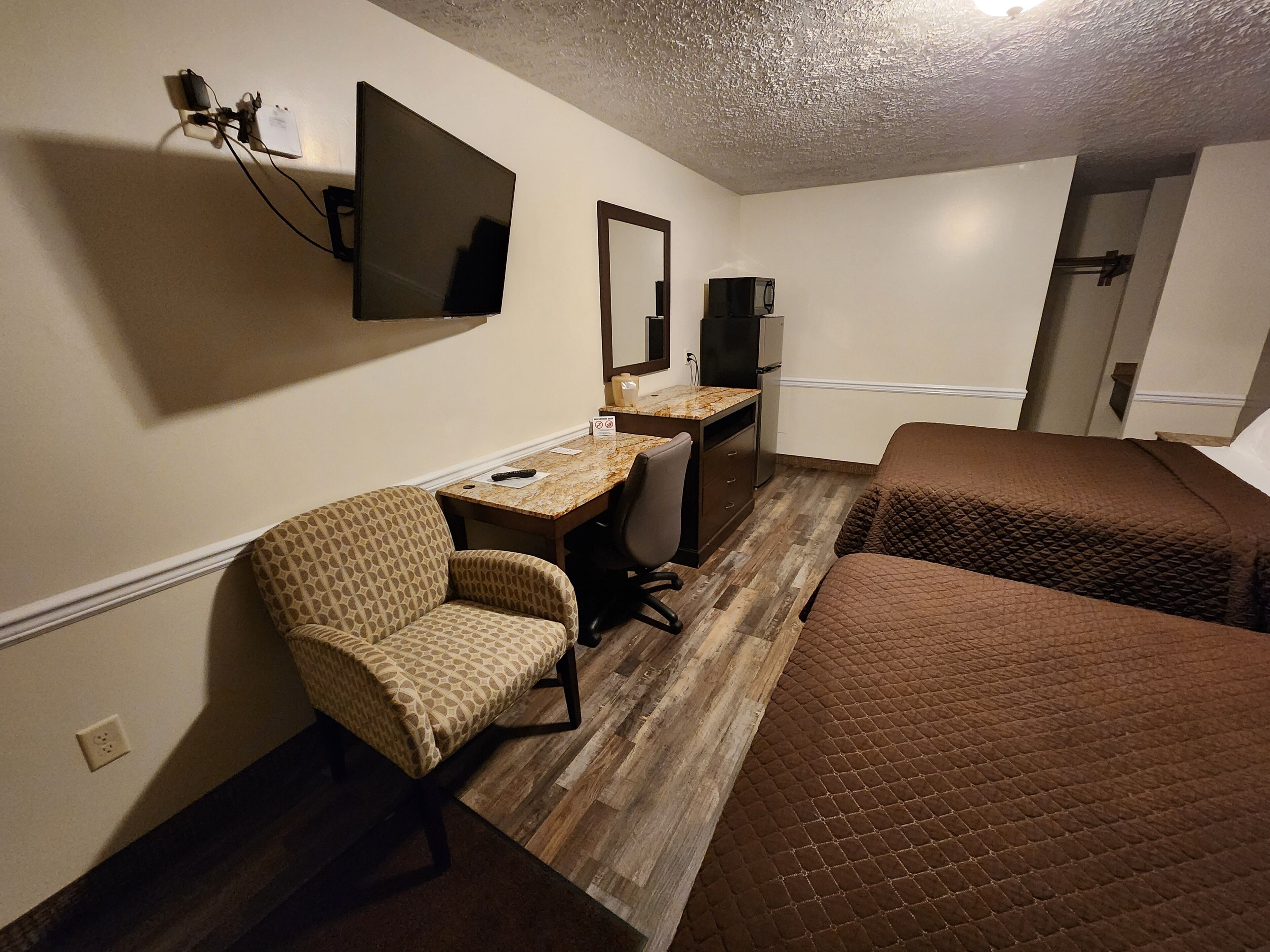 Une chambre d’hôtel équipée d’un bureau, d’une chaise, de deux lits, d’une télévision et d’un four à micro-ondes.