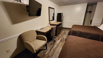 Une chambre d’hôtel équipée d’un bureau, d’une chaise, de deux lits, d’une télévision et d’un four à micro-ondes.