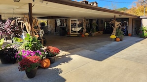 A covered patio area with potted plants, a barbecue grill, and a stone wall.