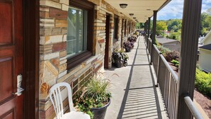 A covered outdoor area with a stone facade, a wooden door, and a row of potted plants.