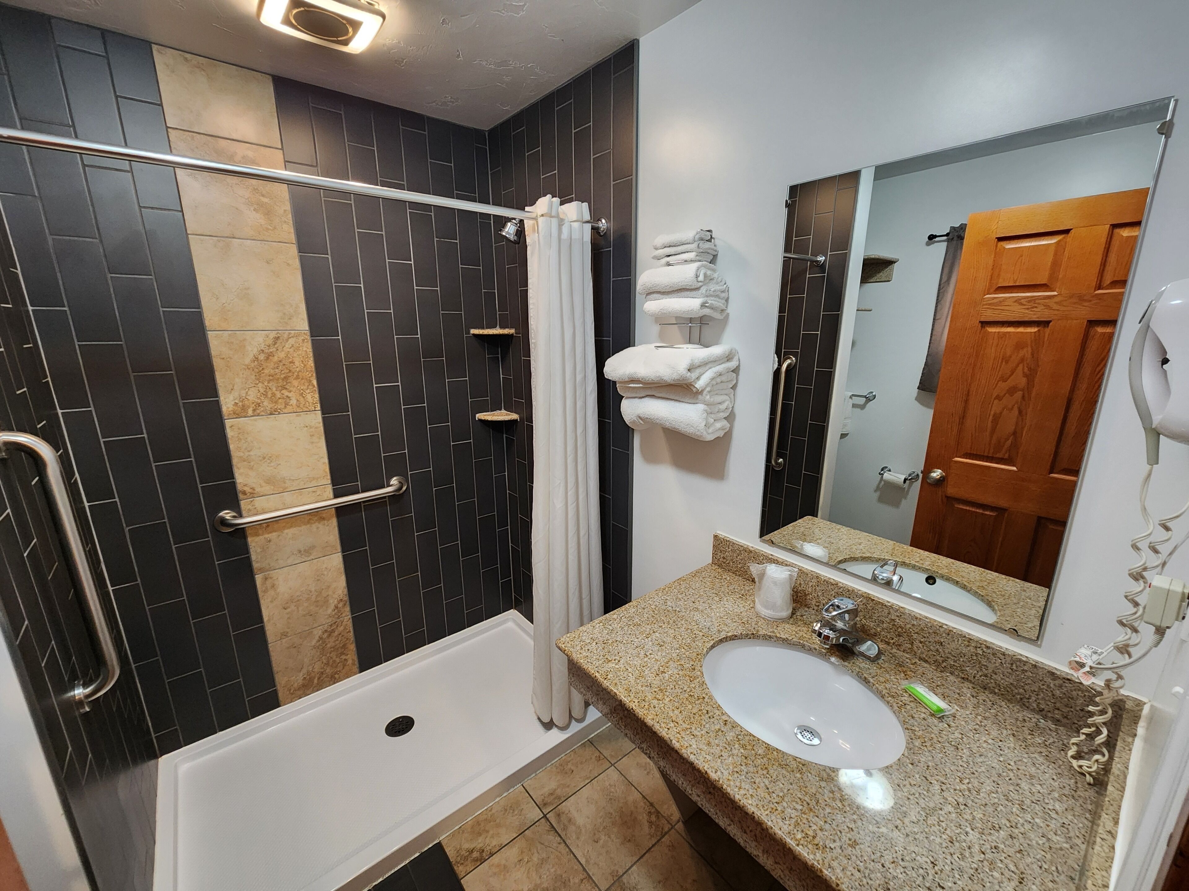 A bathroom with a bathtub, a sink, a mirror, and towels.