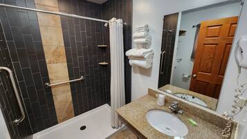 A bathroom with a bathtub, a sink, a mirror, and towels.