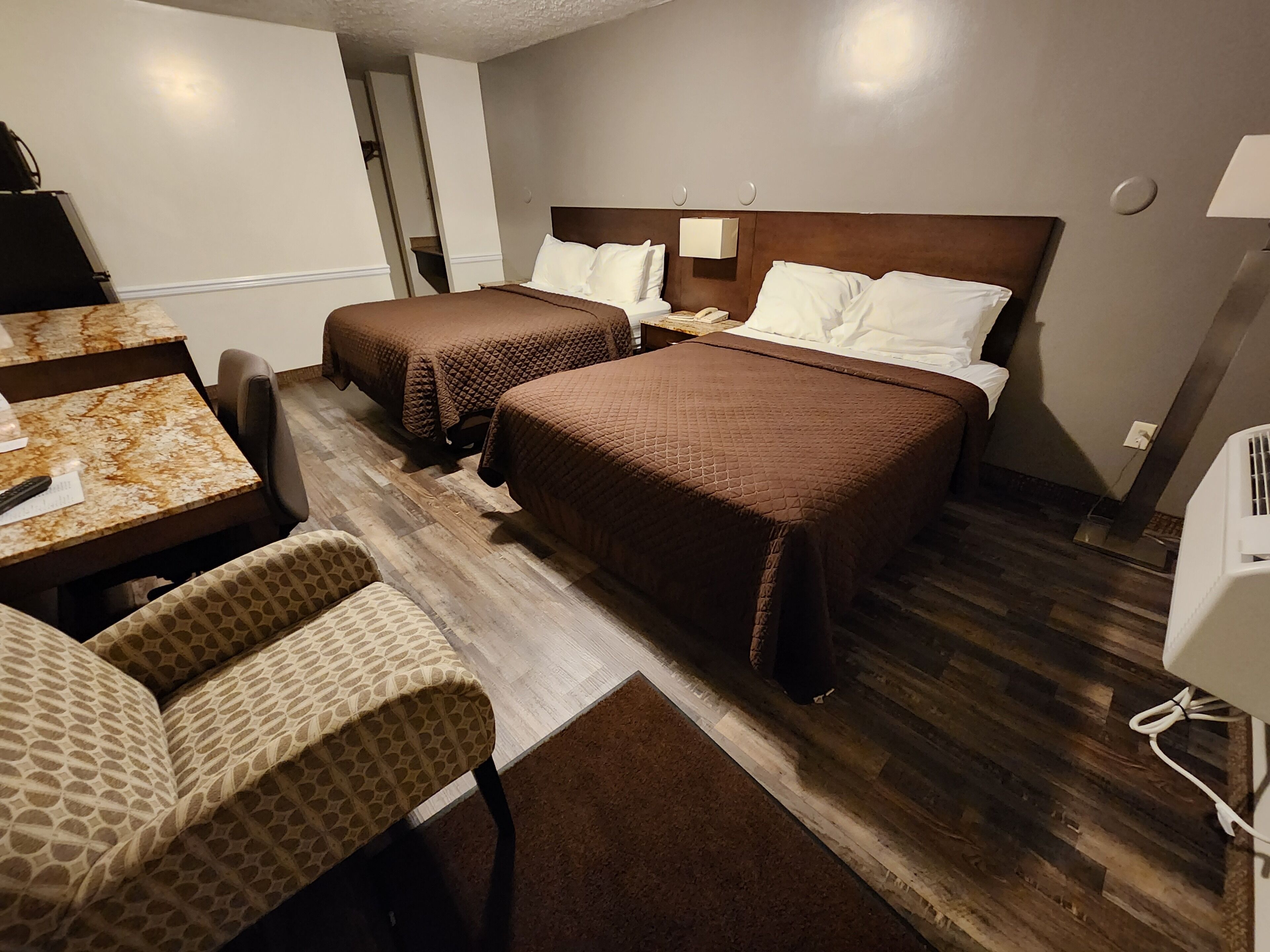 A hotel room with two beds, a desk, and a chair.
