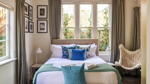 Een slaapkamer met een bed, een stoel, een raam en gordijnen.
