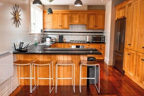 Una cucina moderna con mobili in legno, un piano di lavoro nero e un frigorifero in acciaio inossidabile.