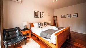 A bedroom with a bed, a chair, a bedside table, a lamp, and a ceiling fan. - Freemans Bay 3BDR Stylist Villa (Auckland)