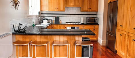 Una cocina moderna con armarios de madera, un refrigerador de acero inoxidable y una isla central con taburetes de bar.