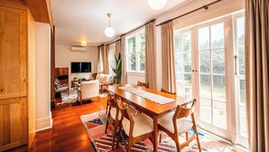 A spacious dining area with a wooden table and chairs, large windows with curtains, and a television in the background. - Freemans Bay 3BDR Stylist Villa (Auckland)