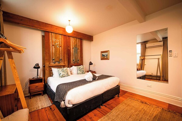Una camera da letto con un letto grande, travi in legno, uno specchio e una scala di legno.