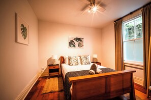 A bedroom with a bed, bedside tables, a nightstand, a window with curtains, and a ceiling fan. - Freemans Bay 3BDR Stylist Villa (Auckland)
