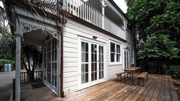 A white building with a wooden deck, large windows, and a balcony. - Freemans Bay 3BDR Stylist Villa (Auckland)