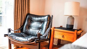 A leather chair, a wooden nightstand with a lamp, and a wooden floor. - Freemans Bay 3BDR Stylist Villa (Auckland)