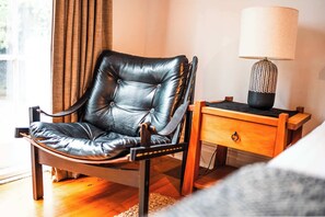 Un fauteuil en cuir, une table de chevet en bois avec une lampe et un plancher en bois.